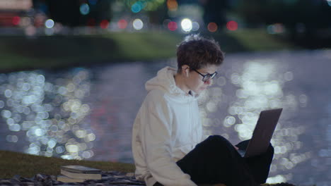 young woman studying with laptop late in the park