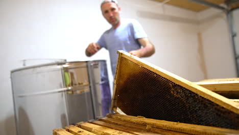 beekeeper takes honey frames from special box and puts them into metal apparatus. apiarist removes honey harvest from honeycombs.
