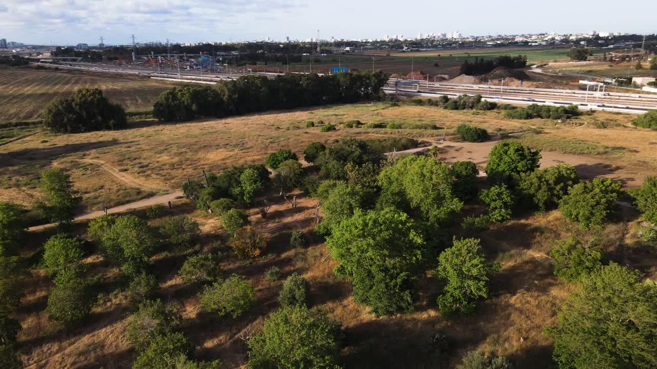 A drone panning above a park looking across the main highway and surrounding fields