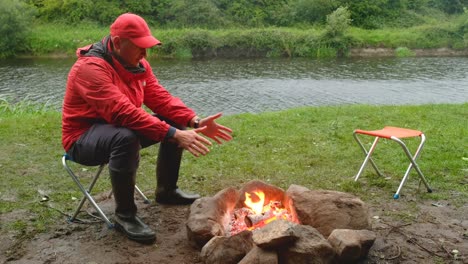 man sitting by the fire warming hands