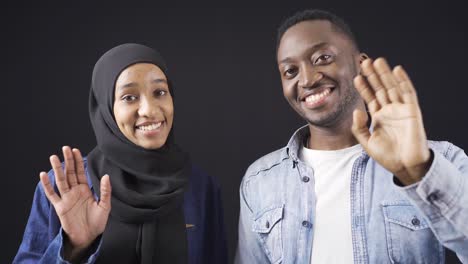 Mujer-Y-Hombre-Musulmán-Africano-En-Relación-Feliz-Mirando-A-La-Cámara-Y-Saludando