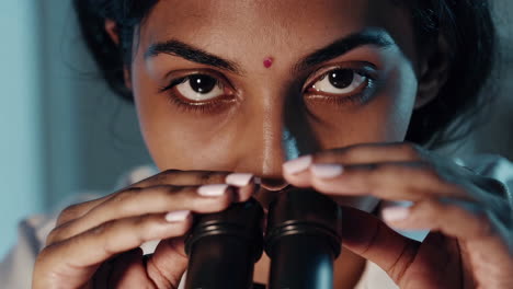 close-up of a female scientist looking into a microscope