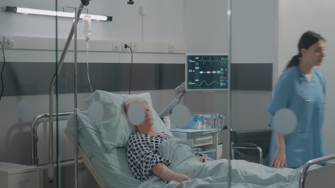 Medical assistant looking at heart rate monitor while patient sleeping