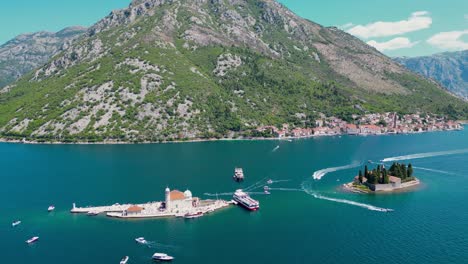 aerial drone view of sveti dorde island. in background is perast city. famous travel destination in montenegro. drone backwards , ascending. tourists boats.