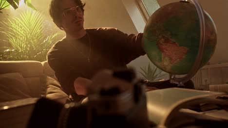 man studying a globe in a cozy living room