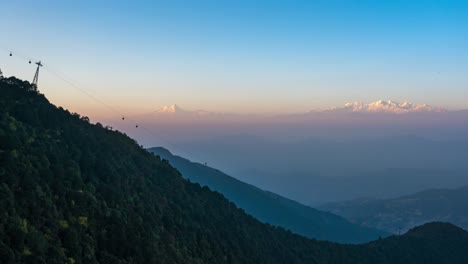 la puesta de sol sobre las montañas del himalaya y un teleférico que sube y baja la montaña en primer plano