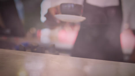 Spots-of-light-against-mid-section-of-barista-serving-coffee-at-cafe