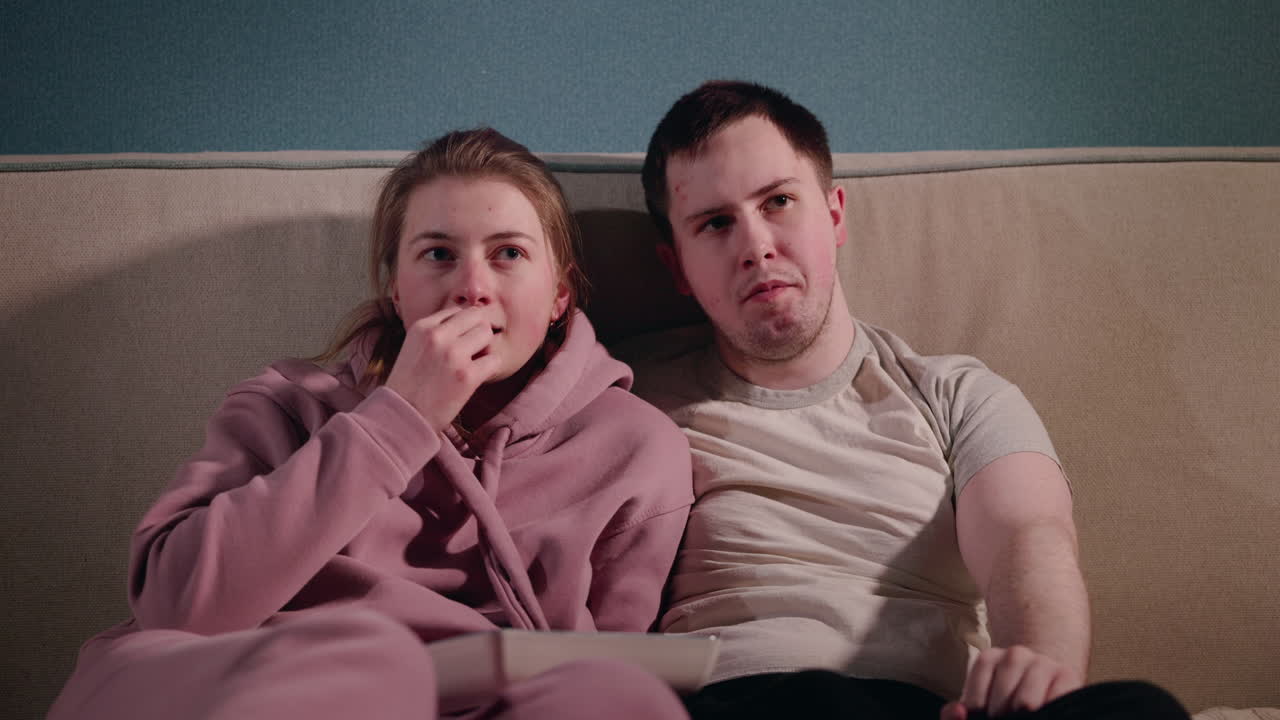 커플 이 소파 에서 휴식을 취 하고 영화 나 비디오 를 보고 있다