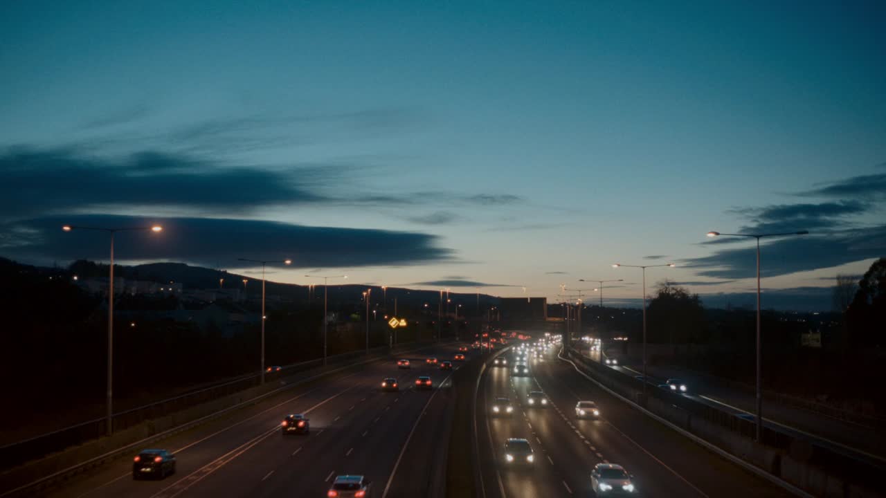 A locked-off shot of vehicles moving along the M50 motorway in Dublin, Ireland. The busy highway captures urban transportation and daily commuting, showing the movement of cars and trucks.