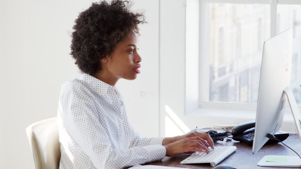 Young black woman working at computer in an office, close up