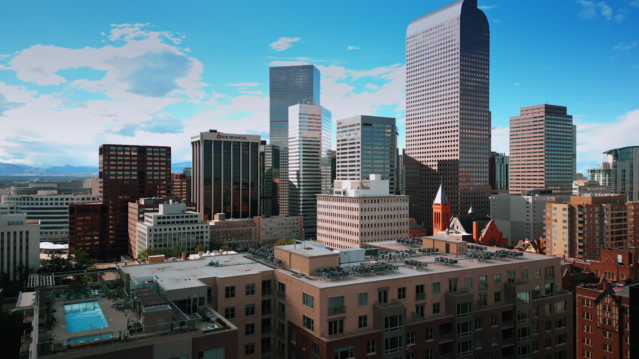 Denver, USA, 28 July 2025: Sun lights the facades of the buildings in the downtown of Denver, Colorado, USA. Beautiful azure sky with white clouds at backdrop