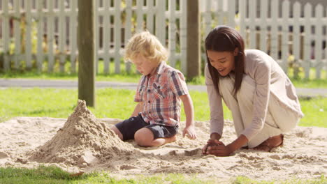 teacher at montessori school playing with male pupil in sand pit