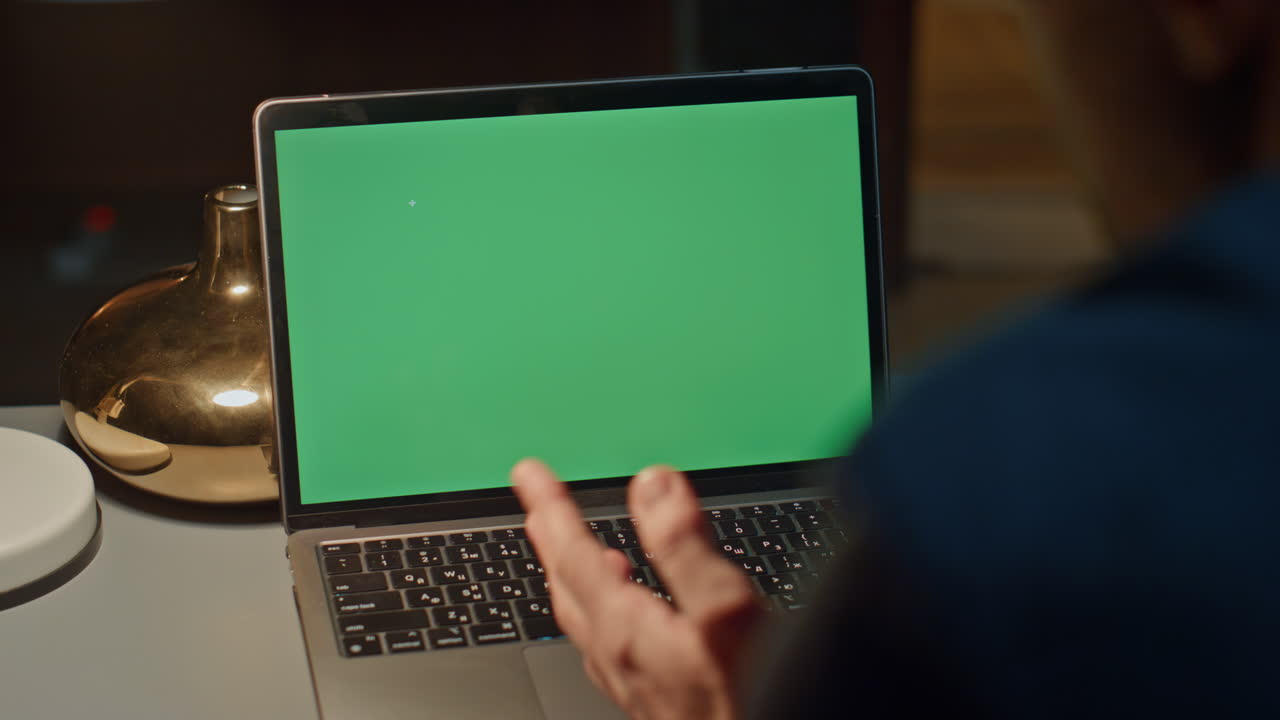 Unknown freelancer using greenscreen laptop video conference at night closeup