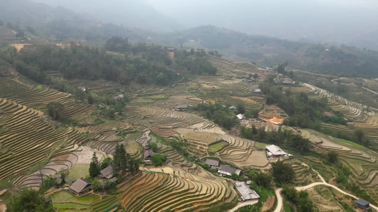 Verdant rice terraces curve gracefully across mountain slopes, with wooden huts overlooking a lush valley and village—capturing the harmony of rural life and nature.