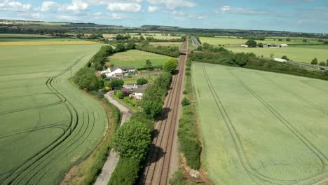 Luftbild-Von-Bahngleisen,-Landwirtschaftlichem-Ackerland-Und-Grünen-Feldern-Und-Blauem-Himmel