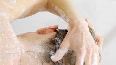 a woman washes her hair with shampoo