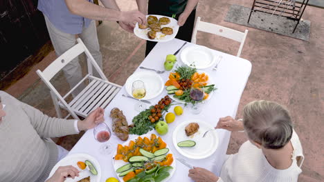 two senior friends are serving the dinner outside 1