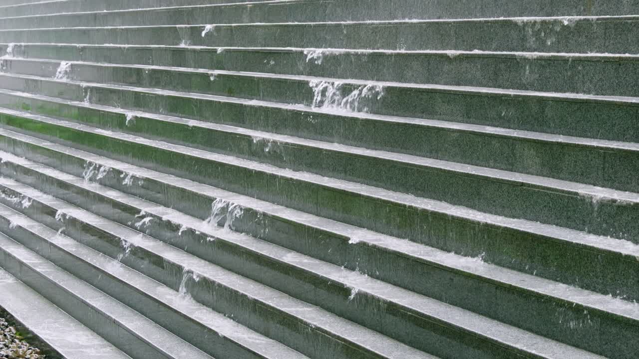Water flows down the textured steps showcasing nature's impact on urban architecture.
