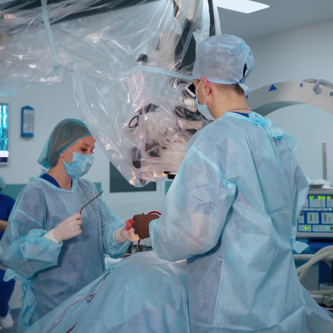 Neurosurgery in advanced clinic. Experienced doctor performs an operation through the microscope. Female assistant works with specialist during surgery.