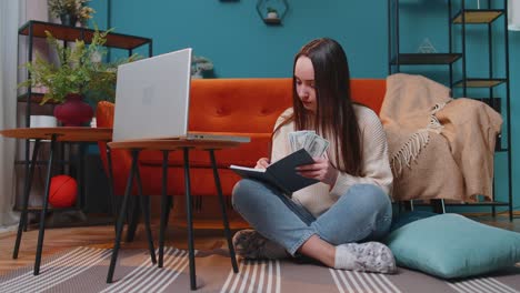 mujer haciendo, planeando el presupuesto de la casa en la computadora portátil y contando dinero, niña comprobando el ingreso en efectivo en dólares