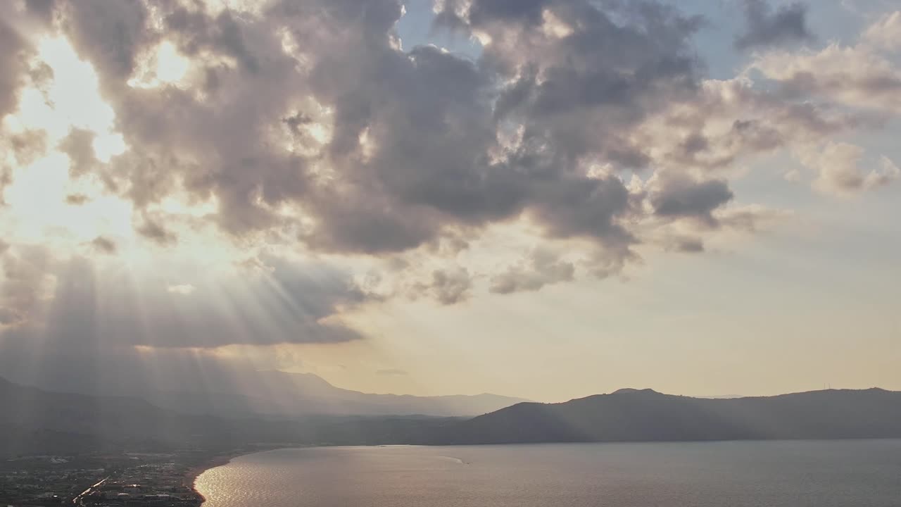Golden Sun Rays Breaking Through Clouds Over a Serene Coastal Bay