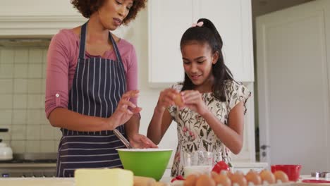 african american mother and daughter baking together in the kitchen at home