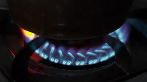 stovetop blue flame of propane gas stove with dark background, close up