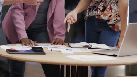 mid section of diverse male and female colleagues in discussion using tablet in office, slow motion