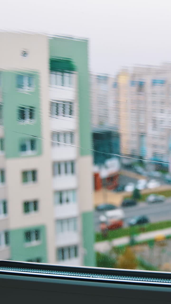 Washing window in the city flat. Man worker cleaning window with a special brush using water on the city background. Vertical video