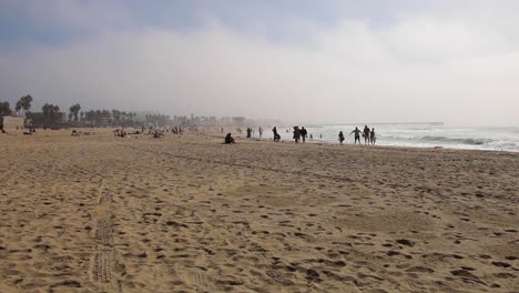 people walking along venice beach as the waves splash in