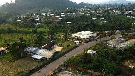 Drone-shot-over-mopeds-and-urban-homes-in-Ebolowa-city,-sunset-in-south-Cameroon