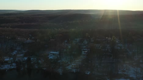 El-Dron-Se-Detiene-Sobre-Las-Casas-Rurales-En-El-Bosque-Al-Borde-De-Un-Lago-En-El-Amanecer-Nevado-De-Invierno