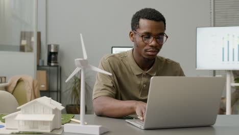 businessman using laptop sitting at table with windmill model in the office 4