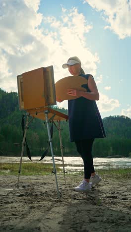 woman painting outdoors by the river