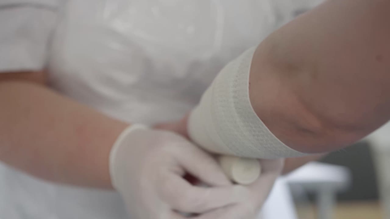 A nurse bandages a patient's arm in a hospital