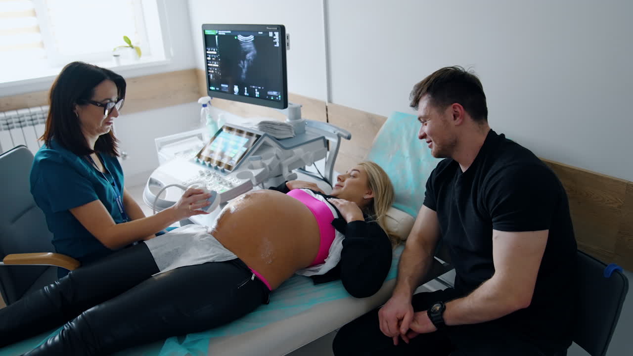 Ultrasonic pregnancy check up. Caucasian couple is having ultrasound examination at doctor's office. Top view.