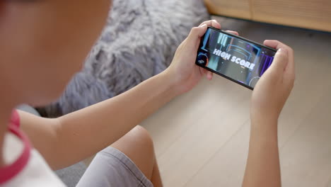 teenage asian boy plays a game on his smartphone at home