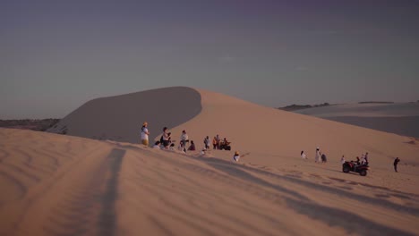 Tourists-walking-and-ATV-riding-on-the-White-Sand-Dunes-in-Sunrise-at-Mui-Ne,-Phan-Thiet,-Vietnam