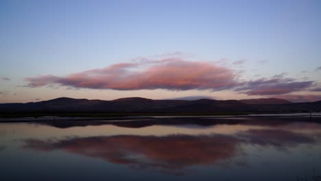 Perfekter-Hintergrund-Und-Blick-Vom-Ufer-Des-Wassers-Und-Die-Berge-Im-Hintergrund,-Orangefarbener-Himmel-Und-Wolken,-Die-Sich-Im-Wasser-Spiegeln