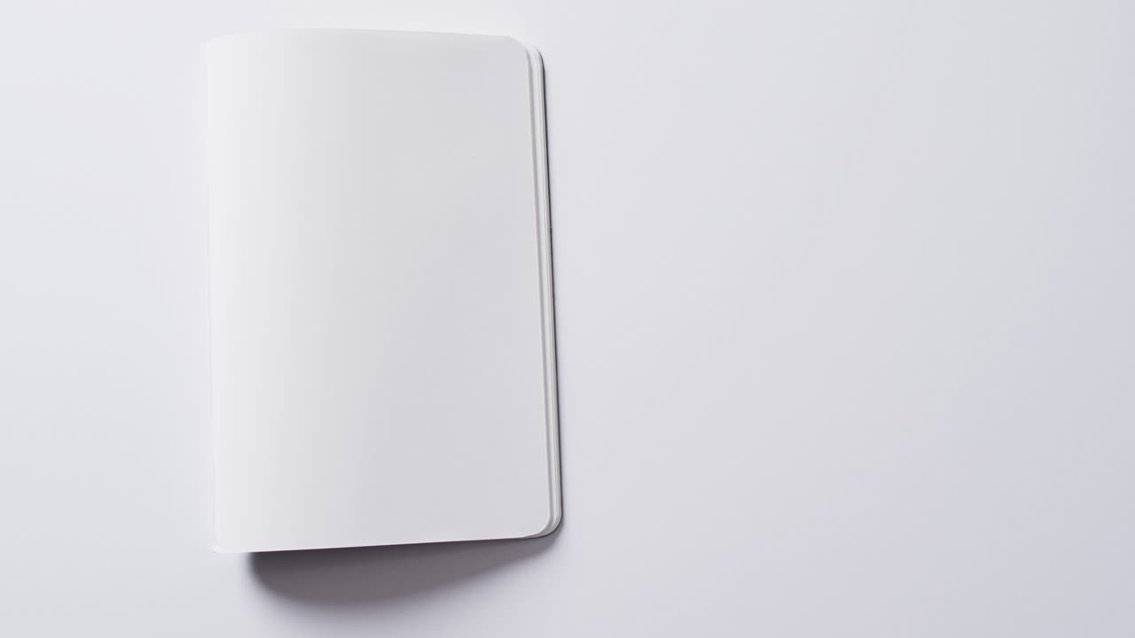 Close up of open blank book with copy space on white background in slow motion