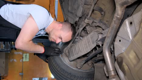 mechanic inspecting car undercarriage at auto service
