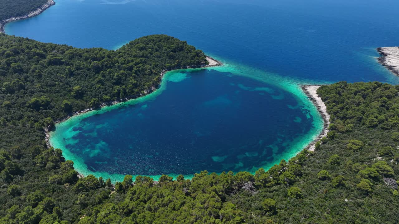 Lagoon by forested coast on Croatian island Mljet, drone parallax