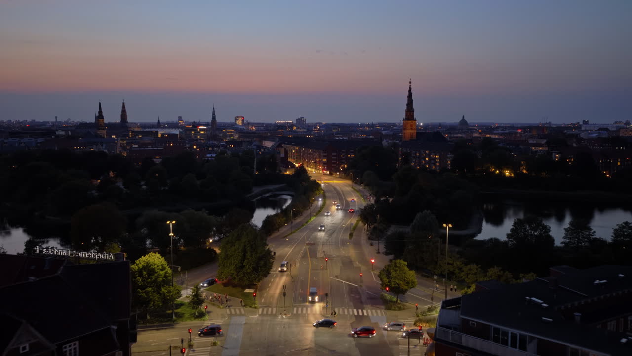 Vista aerea da drone della città con le luci delle auto che brillano lungo l'H.C. Andersens Boulevard e i campanili delle chiese in lontananza, di sera, a Copenaghen, in Danimarca