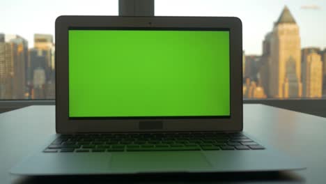 portátil de negocios con pantalla verde monitor de clave croma y fondo de paisaje urbano.