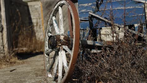 Antique-delipidated-wood-hauling-wagon-parked-outside-a-stone-barn-building-on-a-museum-farm-on-a-sunny-day