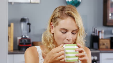 una mujer rubia bebiendo una taza de café.