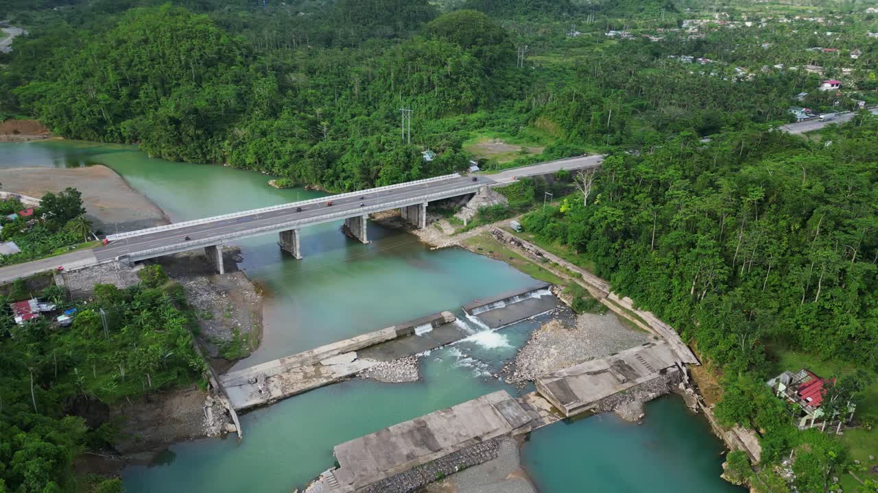 Scenic orbiting aerial view of river dam and bridge surrounded by lush greenery along Sto Domingo River, Catanduanes, Philippines.