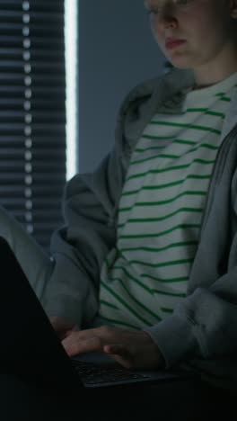 una adolescente usando una computadora portátil por la noche