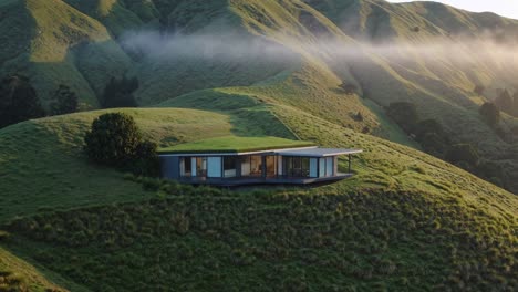 modern house on a hilltop with misty mountains