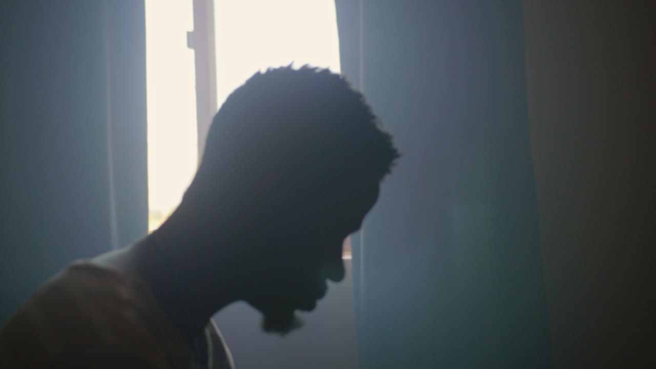 hombre afroamericano sentado en la cama por la mañana mirando su reloj